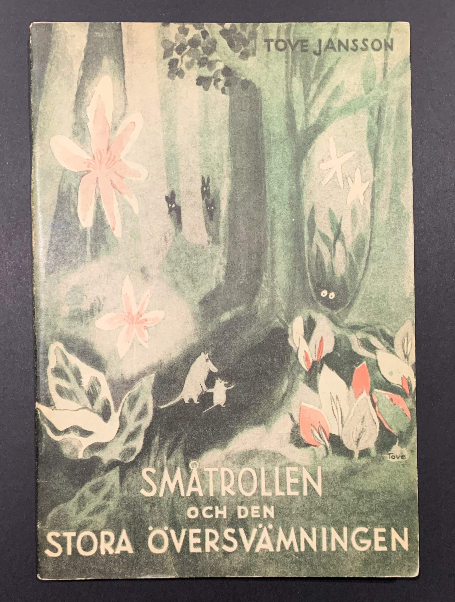 First edition of Tove Jansson's first Moomin book, Småtrollen och den stora översvämningen (1945), showing the original color illustrated softcover | Tove Janssonin ensimmäisen muumikirjan ensipainoksen kansikuva. | Pärmbild av Tove Janssons första muminbok.